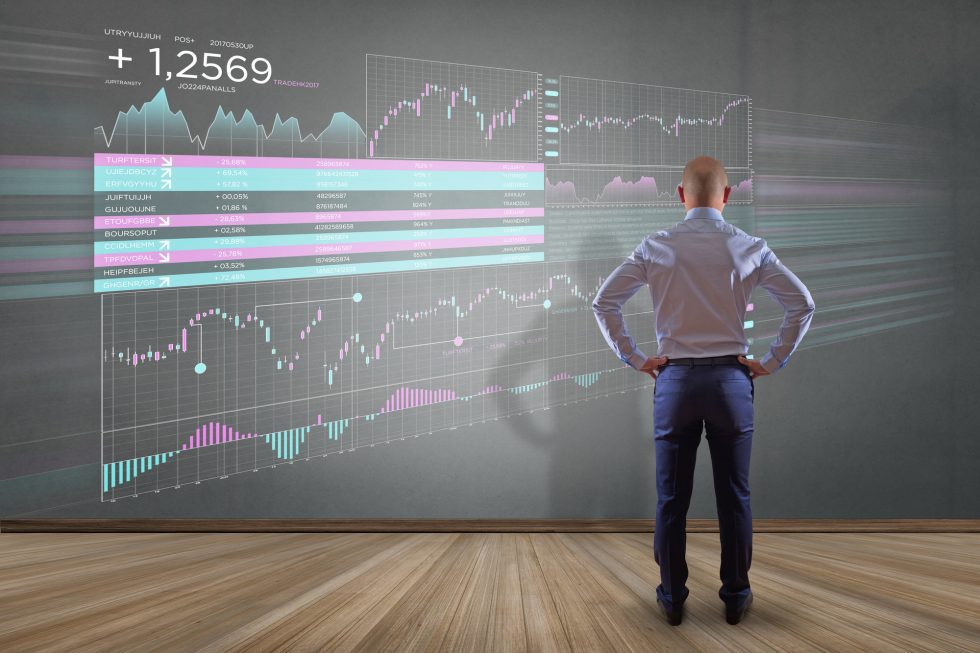 Man standing in front of large Forex charts